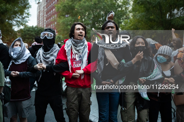 Pro-Palestinian students and their supporters form a protective chain around a temporary Gaza solidarity encampment outside the office of Ge...