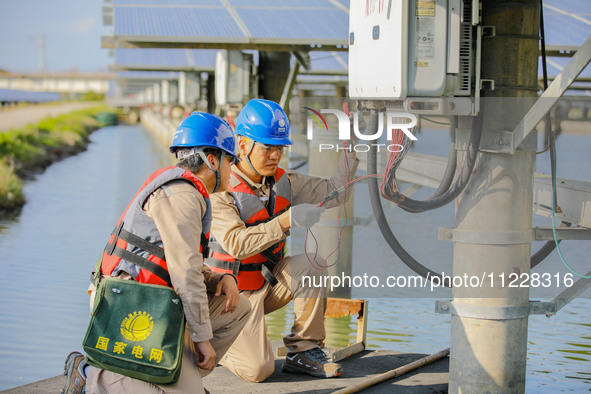 Employees of State Grid Fuzhou Power Supply Company are testing photovoltaic equipment in Xincuo town, Fuqing city, Fujian province, China,...