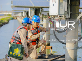 Employees of State Grid Fuzhou Power Supply Company are testing photovoltaic equipment in Xincuo town, Fuqing city, Fujian province, China,...