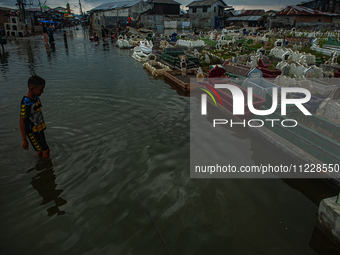 Children are playing at a public cemetery submerged by tidal floods in the Belawan area, Medan, Indonesia, on May 11, 2024. (