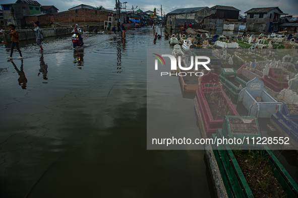 Children are playing at a public cemetery submerged by tidal floods in the Belawan area, Medan, Indonesia, on May 11, 2024. 