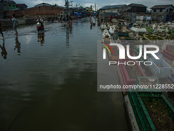 Children are playing at a public cemetery submerged by tidal floods in the Belawan area, Medan, Indonesia, on May 11, 2024. (