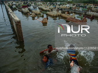 Children are playing at a public cemetery submerged by tidal floods in the Belawan area, Medan, Indonesia, on May 11, 2024. (