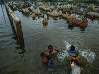 Children are playing at a public cemetery submerged by tidal floods in the Belawan area, Medan, Indonesia, on May 11, 2024. (