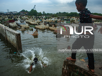 Children are playing at a public cemetery submerged by tidal floods in the Belawan area, Medan, Indonesia, on May 11, 2024. (