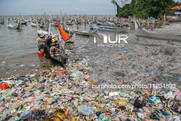 A number of fishing boats are on a beach full of rubbish, mostly plastics, in the Kwanyar district, Bangkalan, Madura Island, Indonesia, on...