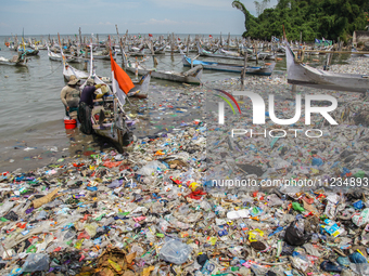 A number of fishing boats are on a beach full of rubbish, mostly plastics, in the Kwanyar district, Bangkalan, Madura Island, Indonesia, on...