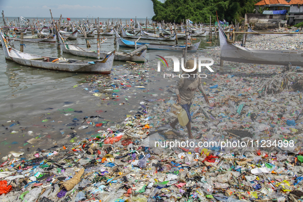 A number of fishing boats are on a beach full of rubbish, mostly plastics, in the Kwanyar district, Bangkalan, Madura Island, Indonesia, on...