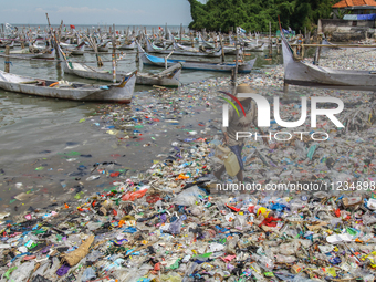 A number of fishing boats are on a beach full of rubbish, mostly plastics, in the Kwanyar district, Bangkalan, Madura Island, Indonesia, on...