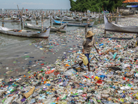 A number of fishing boats are on a beach full of rubbish, mostly plastics, in the Kwanyar district, Bangkalan, Madura Island, Indonesia, on...