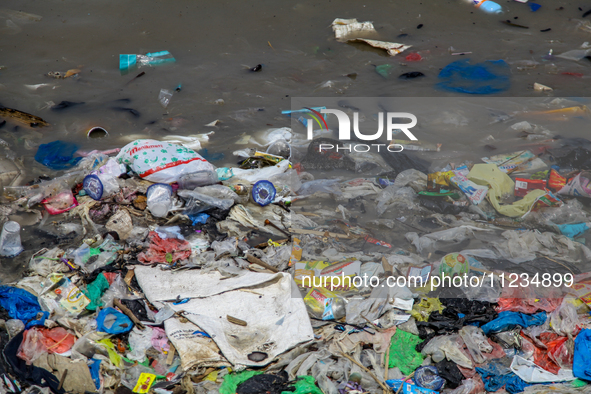 A number of fishing boats are on a beach full of rubbish, mostly plastics, in the Kwanyar district, Bangkalan, Madura Island, Indonesia, on...