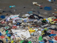 A number of fishing boats are on a beach full of rubbish, mostly plastics, in the Kwanyar district, Bangkalan, Madura Island, Indonesia, on...