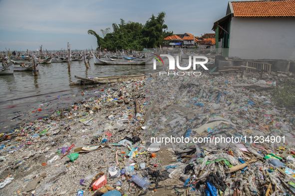 A number of fishing boats are on a beach full of rubbish, mostly plastics, in the Kwanyar district, Bangkalan, Madura Island, Indonesia, on...