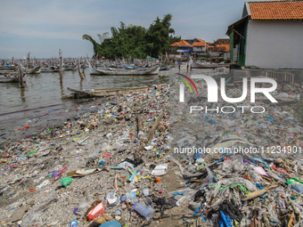 A number of fishing boats are on a beach full of rubbish, mostly plastics, in the Kwanyar district, Bangkalan, Madura Island, Indonesia, on...