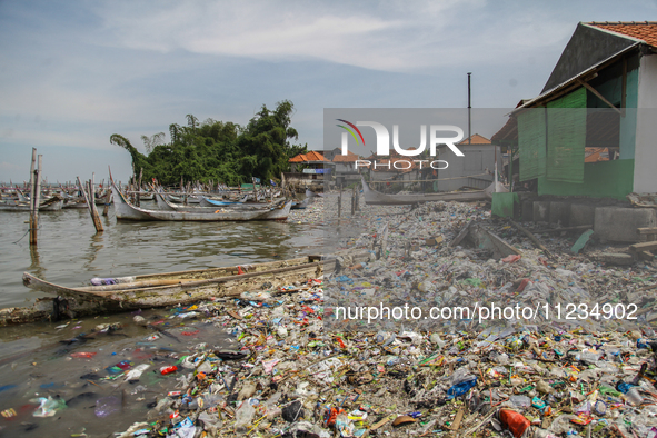 A number of fishing boats are on a beach full of rubbish, mostly plastics, in the Kwanyar district, Bangkalan, Madura Island, Indonesia, on...