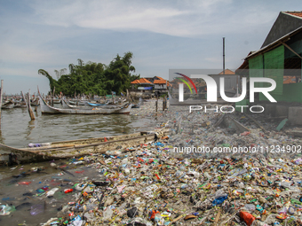 A number of fishing boats are on a beach full of rubbish, mostly plastics, in the Kwanyar district, Bangkalan, Madura Island, Indonesia, on...