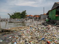 A number of fishing boats are on a beach full of rubbish, mostly plastics, in the Kwanyar district, Bangkalan, Madura Island, Indonesia, on...