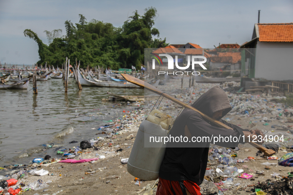 A number of fishing boats are on a beach full of rubbish, mostly plastics, in the Kwanyar district, Bangkalan, Madura Island, Indonesia, on...