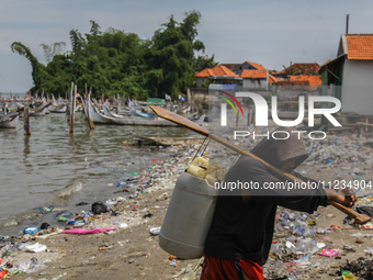 A number of fishing boats are on a beach full of rubbish, mostly plastics, in the Kwanyar district, Bangkalan, Madura Island, Indonesia, on...