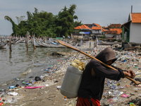 A number of fishing boats are on a beach full of rubbish, mostly plastics, in the Kwanyar district, Bangkalan, Madura Island, Indonesia, on...