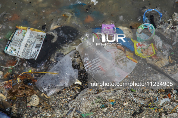 A number of fishing boats are on a beach full of rubbish, mostly plastics, in the Kwanyar district, Bangkalan, Madura Island, Indonesia, on...