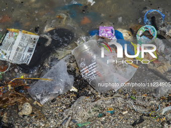 A number of fishing boats are on a beach full of rubbish, mostly plastics, in the Kwanyar district, Bangkalan, Madura Island, Indonesia, on...