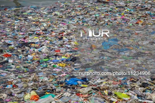 A number of fishing boats are on a beach full of rubbish, mostly plastics, in the Kwanyar district, Bangkalan, Madura Island, Indonesia, on...