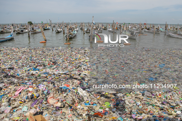 A number of fishing boats are on a beach full of rubbish, mostly plastics, in the Kwanyar district, Bangkalan, Madura Island, Indonesia, on...