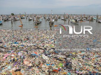 A number of fishing boats are on a beach full of rubbish, mostly plastics, in the Kwanyar district, Bangkalan, Madura Island, Indonesia, on...