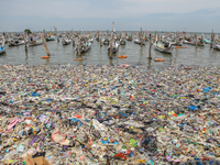 A number of fishing boats are on a beach full of rubbish, mostly plastics, in the Kwanyar district, Bangkalan, Madura Island, Indonesia, on...