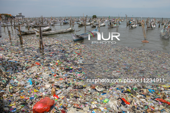 A number of fishing boats are on a beach full of rubbish, mostly plastics, in the Kwanyar district, Bangkalan, Madura Island, Indonesia, on...