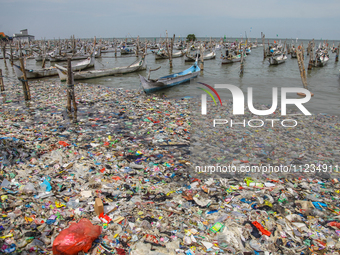 A number of fishing boats are on a beach full of rubbish, mostly plastics, in the Kwanyar district, Bangkalan, Madura Island, Indonesia, on...