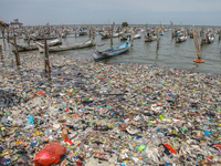 A number of fishing boats are on a beach full of rubbish, mostly plastics, in the Kwanyar district, Bangkalan, Madura Island, Indonesia, on...