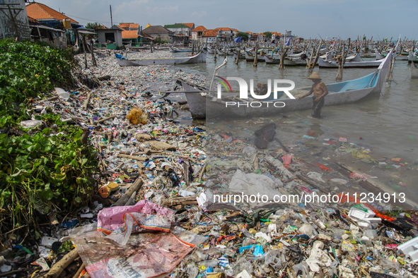 A number of fishing boats are on a beach full of rubbish, mostly plastics, in the Kwanyar district, Bangkalan, Madura Island, Indonesia, on...