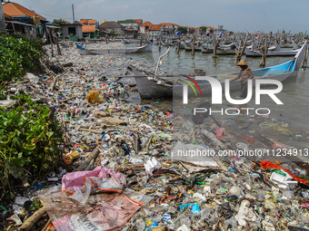 A number of fishing boats are on a beach full of rubbish, mostly plastics, in the Kwanyar district, Bangkalan, Madura Island, Indonesia, on...