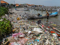 A number of fishing boats are on a beach full of rubbish, mostly plastics, in the Kwanyar district, Bangkalan, Madura Island, Indonesia, on...