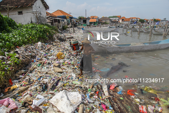 A number of fishing boats are on a beach full of rubbish, mostly plastics, in the Kwanyar district, Bangkalan, Madura Island, Indonesia, on...