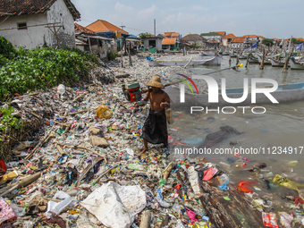 A number of fishing boats are on a beach full of rubbish, mostly plastics, in the Kwanyar district, Bangkalan, Madura Island, Indonesia, on...