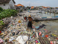 A number of fishing boats are on a beach full of rubbish, mostly plastics, in the Kwanyar district, Bangkalan, Madura Island, Indonesia, on...