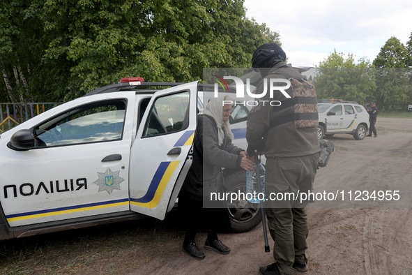 An officer is helping an elderly woman out of a police car during the evacuation of the civilian population from Vovchansk city, which is co...