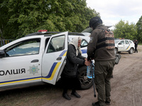 An officer is helping an elderly woman out of a police car during the evacuation of the civilian population from Vovchansk city, which is co...