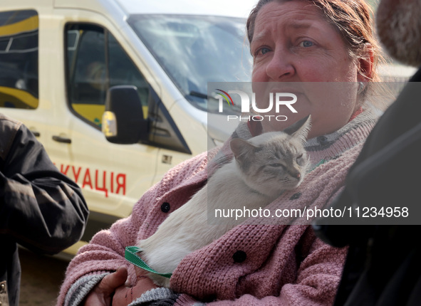 A woman with a cat is being seen during the evacuation of the civilian population from Vovchansk city, which is constantly subjected to Russ...