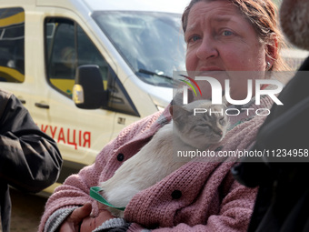 A woman with a cat is being seen during the evacuation of the civilian population from Vovchansk city, which is constantly subjected to Russ...