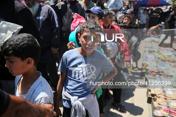 Displaced Palestinians are queuing to receive food rations from a public kitchen in Deir el-Balah in the central Gaza Strip on May 13, 2024,...