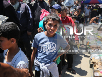 Displaced Palestinians are queuing to receive food rations from a public kitchen in Deir el-Balah in the central Gaza Strip on May 13, 2024,...