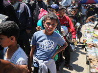 Displaced Palestinians are queuing to receive food rations from a public kitchen in Deir el-Balah in the central Gaza Strip on May 13, 2024,...