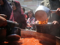 Displaced Palestinians are receiving food portions from a large pot at a public kitchen in Deir el-Balah in the central Gaza Strip on May 13...