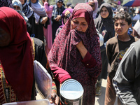 Displaced Palestinians are queuing to receive food rations from a public kitchen in Deir el-Balah in the central Gaza Strip on May 13, 2024,...