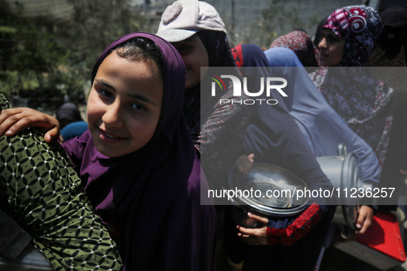 Displaced Palestinians are queuing to receive food rations from a public kitchen in Deir el-Balah in the central Gaza Strip on May 13, 2024,...