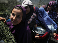 Displaced Palestinians are queuing to receive food rations from a public kitchen in Deir el-Balah in the central Gaza Strip on May 13, 2024,...